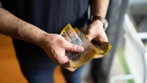 IT Graduate Salaries in Australia: Complete 2025 Guide with Real Numbers 2 A man shuffling Australia dollars ($50 notes) in his hands
