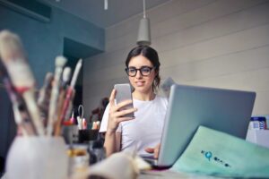 How to Use LinkedIn Effectively for Networking: A Complete Guide for Career Success 2 Woman looking at LinkedIn on her mobile phone trying to improve on networking, whilst at her creative studio.