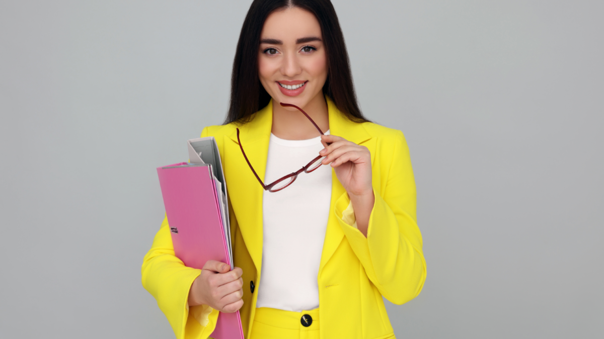 Woman in yellow suite holding binder in her right hand, looking for internship opportunities